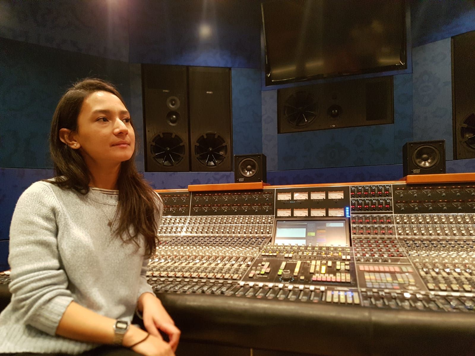 Rebecca Baatjes seated at a large-format mixing console in a recording studio